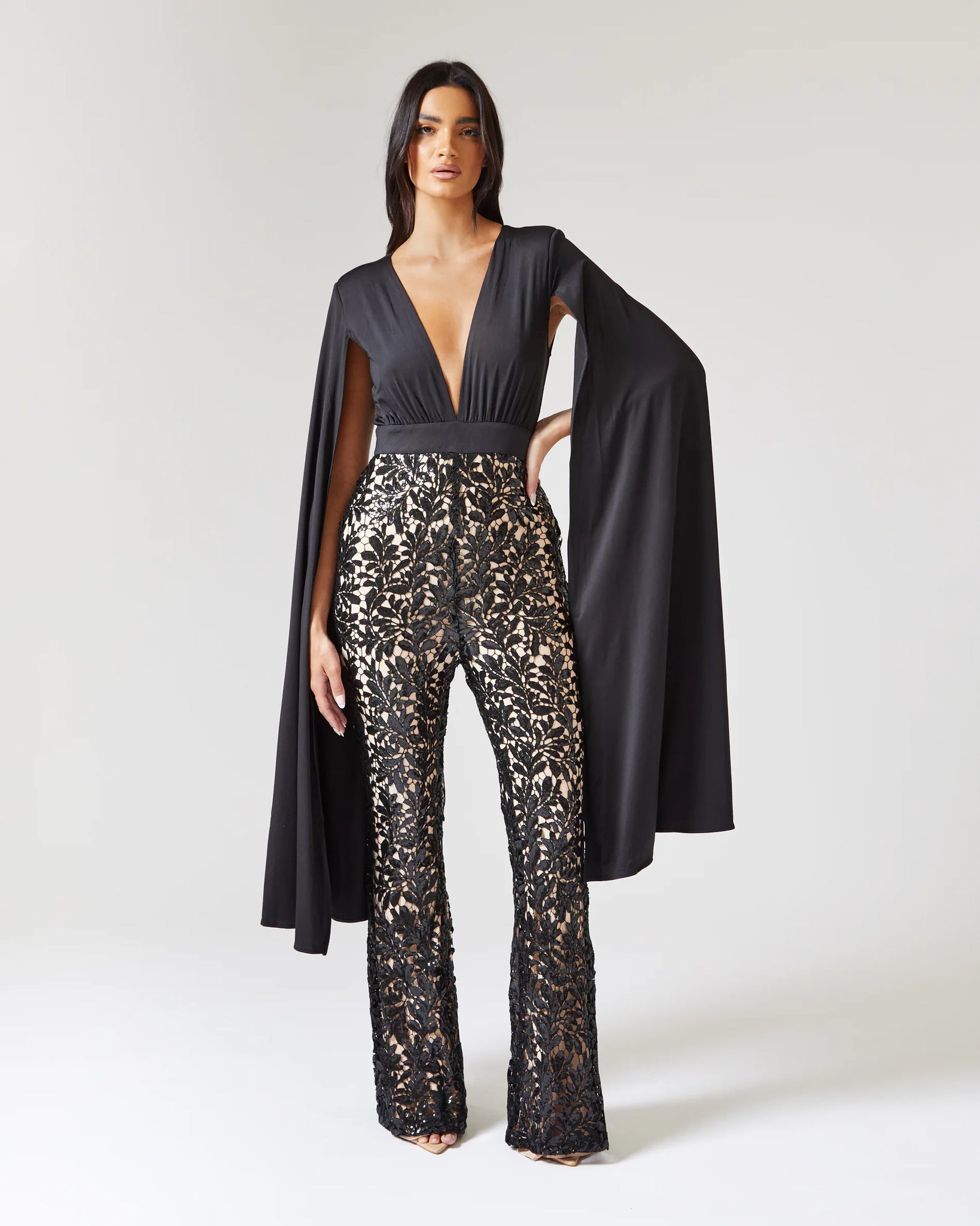 BLACK CAPE SLEEVE JUMPSUIT WITH SEQUIN TROUSER AND CONTRAST NUDE
